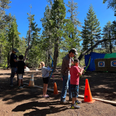 Children outside with instructors during archery practice.