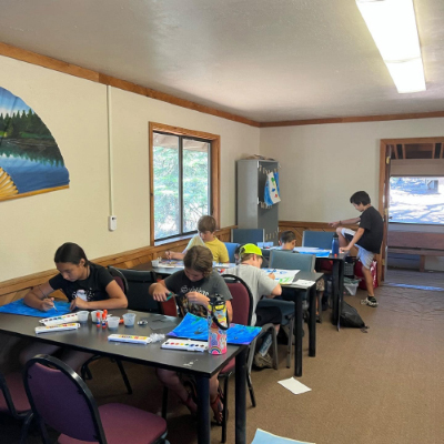 Children in a cabin painting with water colors.